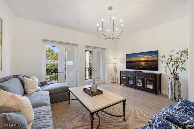 living area with light wood-style floors, baseboards, an inviting chandelier, and french doors