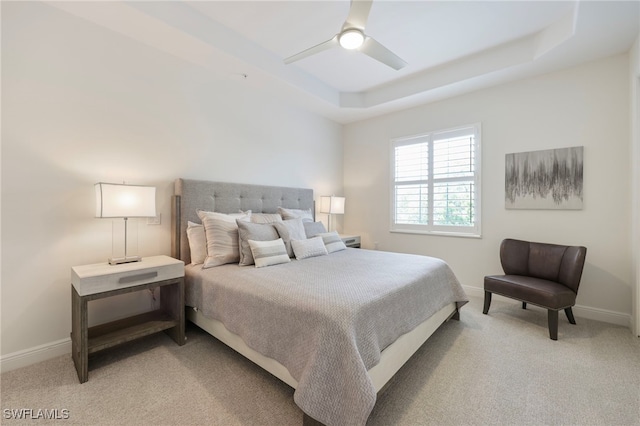 bedroom featuring baseboards, a tray ceiling, and light colored carpet