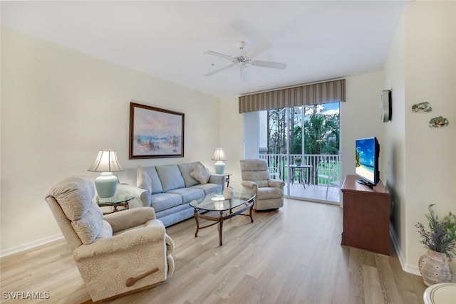 living area featuring light wood-style floors, baseboards, and a ceiling fan