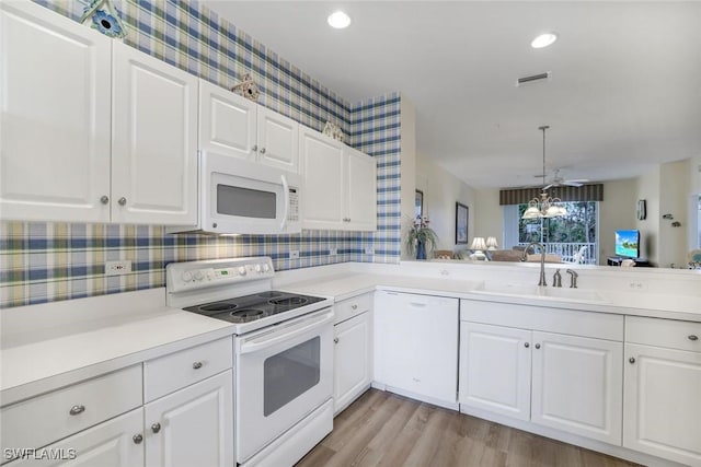 kitchen featuring white appliances, visible vents, light countertops, white cabinetry, and a sink