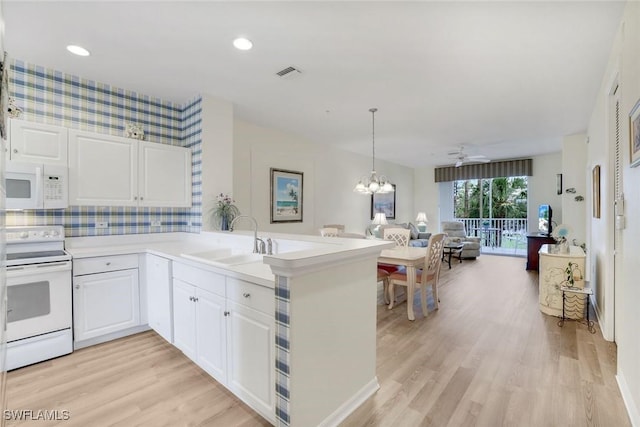 kitchen with a peninsula, white appliances, a sink, visible vents, and open floor plan