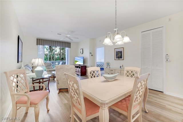 dining space with ceiling fan with notable chandelier, light wood-type flooring, and baseboards