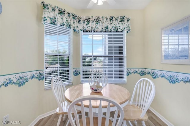 dining area with wainscoting, ceiling fan, baseboards, and wood finished floors