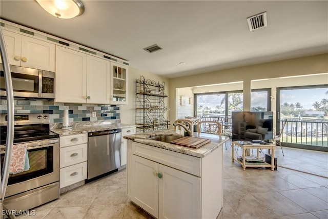 kitchen featuring appliances with stainless steel finishes, a sink, visible vents, and decorative backsplash