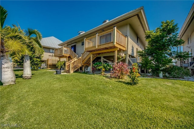 rear view of property with a deck, a lawn, and stairway