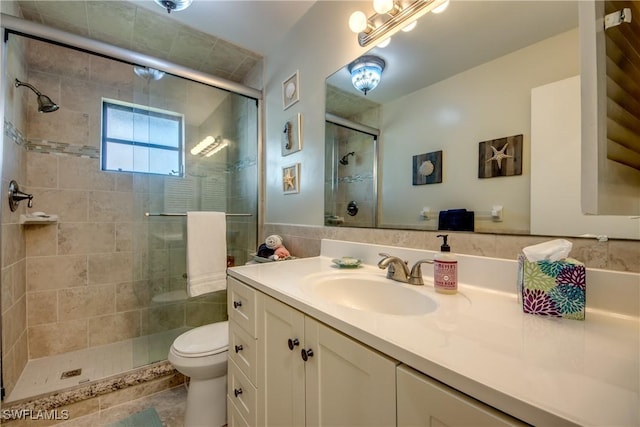 bathroom with a shower stall, toilet, and vanity