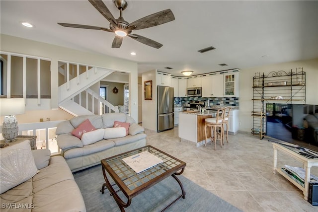 living area featuring visible vents, a ceiling fan, stairs, light tile patterned flooring, and recessed lighting