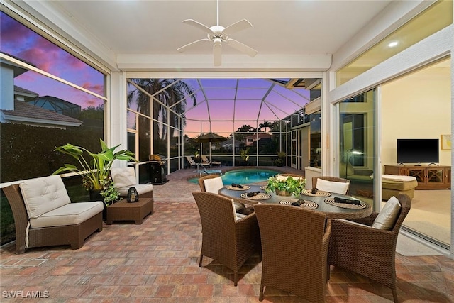 view of patio / terrace featuring glass enclosure, an outdoor pool, and a ceiling fan