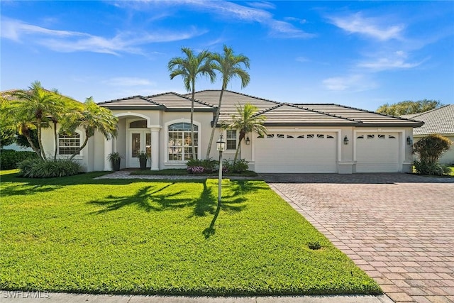 view of front of house with a garage, a tiled roof, decorative driveway, stucco siding, and a front yard