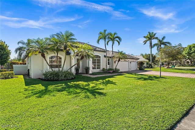 mediterranean / spanish-style house with driveway, stucco siding, an attached garage, and a front yard