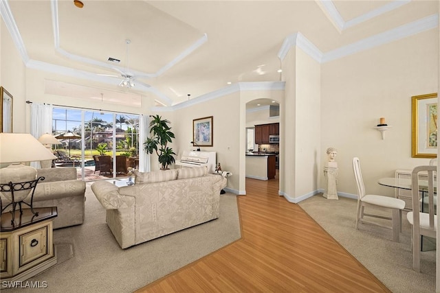 living room featuring arched walkways, visible vents, light wood-style flooring, ornamental molding, and baseboards