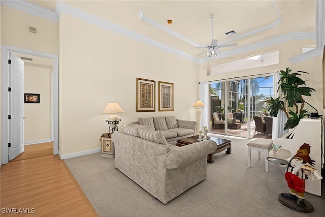 living area with baseboards, wood finished floors, a ceiling fan, and crown molding