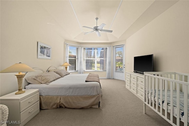 bedroom featuring lofted ceiling, a raised ceiling, a ceiling fan, and light colored carpet