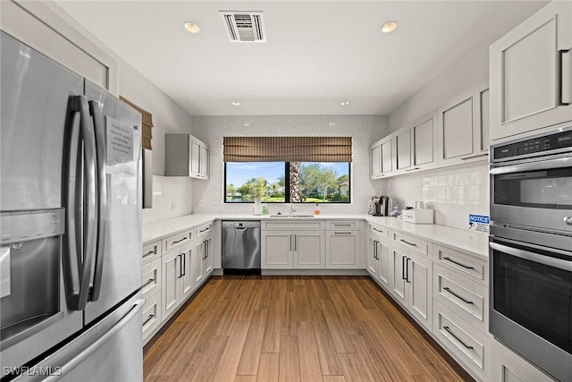 kitchen with tasteful backsplash, recessed lighting, visible vents, appliances with stainless steel finishes, and wood finished floors