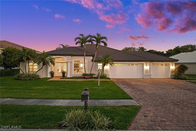 ranch-style home with an attached garage, a front lawn, decorative driveway, and stucco siding