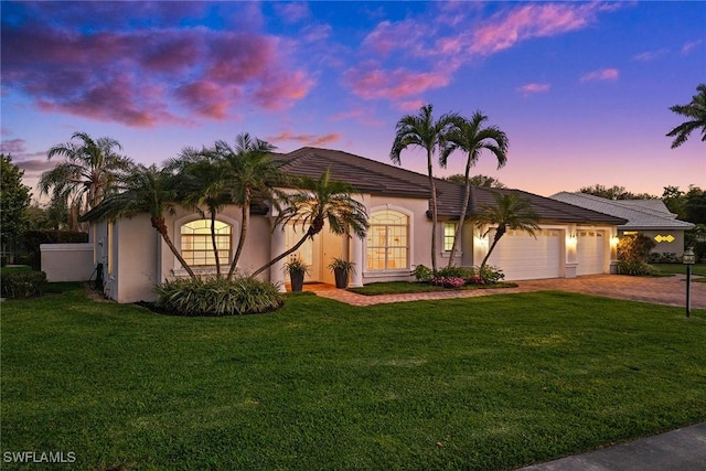 view of front facade with a garage, decorative driveway, french doors, a front lawn, and stucco siding