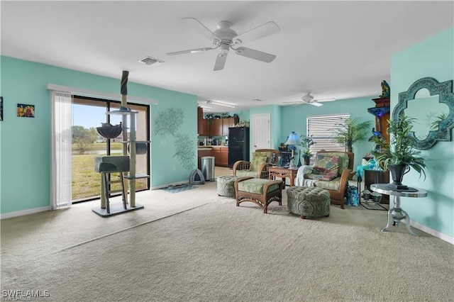 living area with light carpet, ceiling fan, visible vents, and baseboards