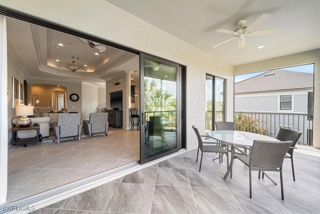 sunroom / solarium featuring a tray ceiling, ceiling fan, and arched walkways