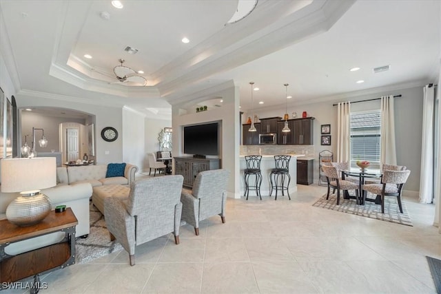 living area featuring ornamental molding, arched walkways, a raised ceiling, and visible vents