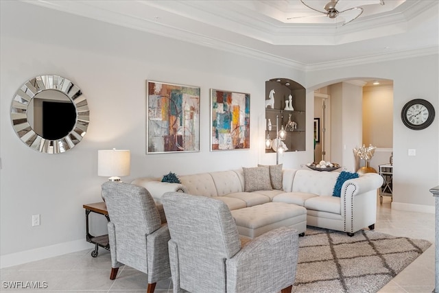 living room with arched walkways, baseboards, crown molding, and a tray ceiling