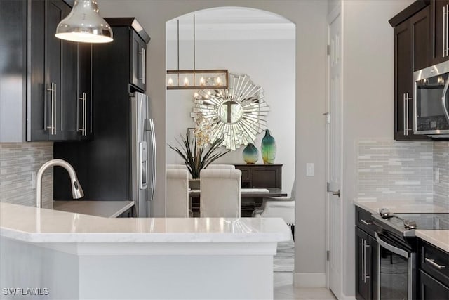 kitchen with a chandelier, stainless steel appliances, decorative backsplash, and decorative light fixtures