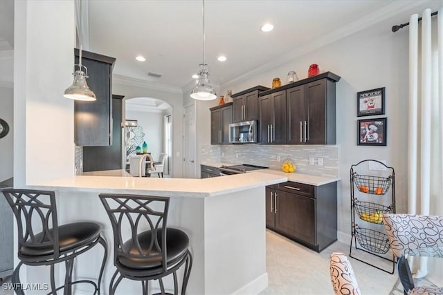 kitchen featuring arched walkways, light countertops, visible vents, appliances with stainless steel finishes, and ornamental molding