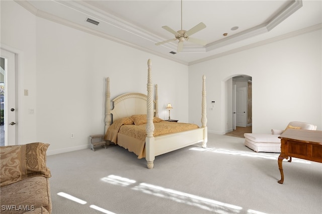 carpeted bedroom featuring visible vents, crown molding, baseboards, a tray ceiling, and arched walkways