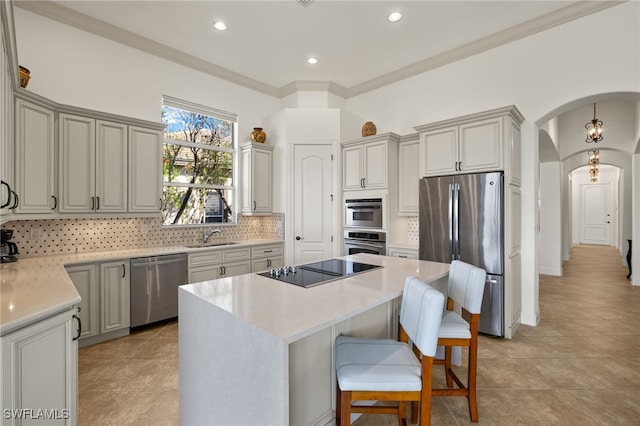 kitchen with tasteful backsplash, a kitchen island, appliances with stainless steel finishes, arched walkways, and a sink