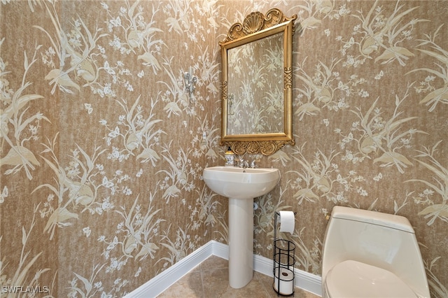 half bathroom featuring tile patterned floors, toilet, and baseboards