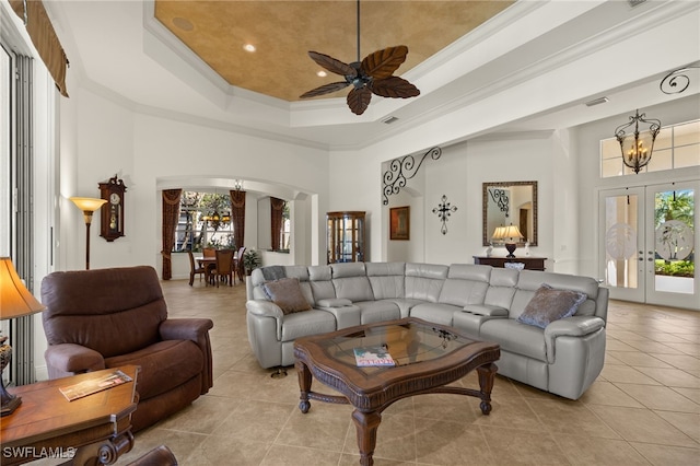 living room with a healthy amount of sunlight, crown molding, french doors, arched walkways, and a raised ceiling