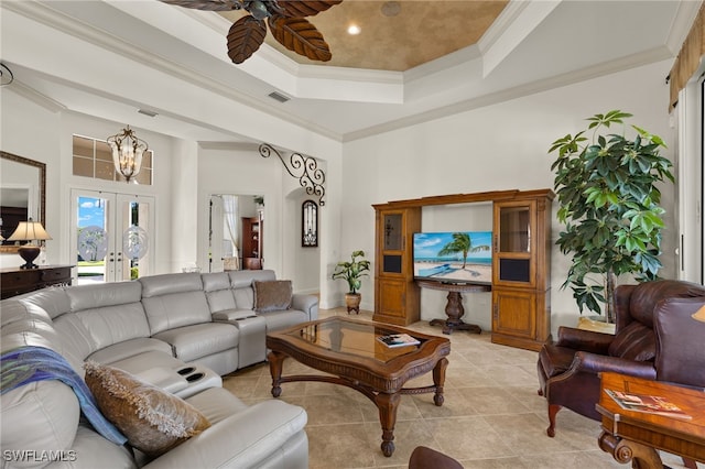 living area featuring a tray ceiling, french doors, crown molding, light tile patterned floors, and ceiling fan