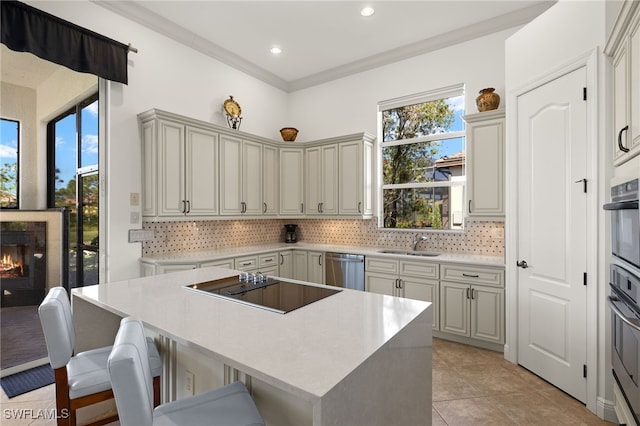 kitchen with a breakfast bar area, a warm lit fireplace, a sink, stainless steel dishwasher, and a center island