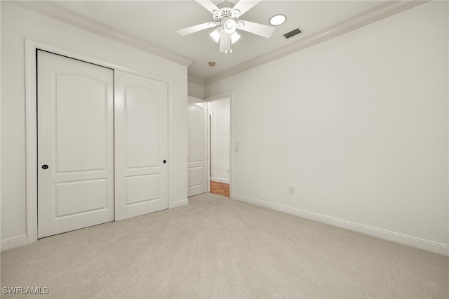 unfurnished bedroom featuring carpet, baseboards, visible vents, ornamental molding, and a closet