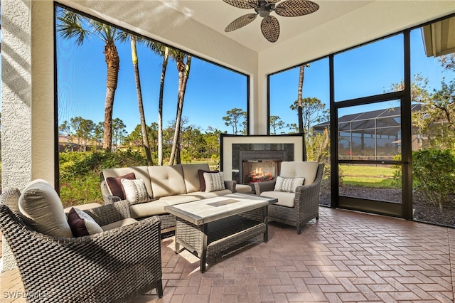 sunroom featuring a lit fireplace and ceiling fan