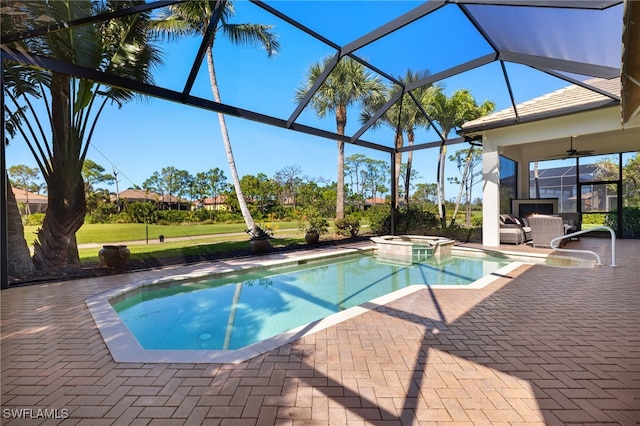 view of pool with a pool with connected hot tub, ceiling fan, a lanai, a yard, and a patio area