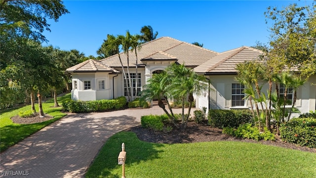 view of front of house featuring stucco siding, a tiled roof, decorative driveway, and a front yard