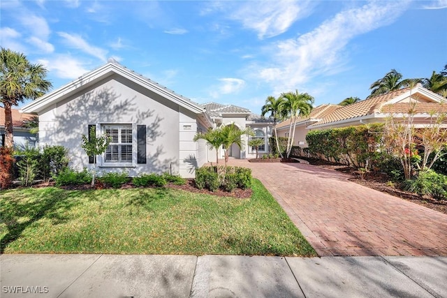 mediterranean / spanish-style house with a front lawn, decorative driveway, a tile roof, and stucco siding