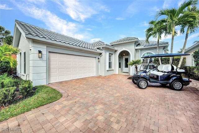 view of front of home with a tile roof, an attached garage, and stucco siding