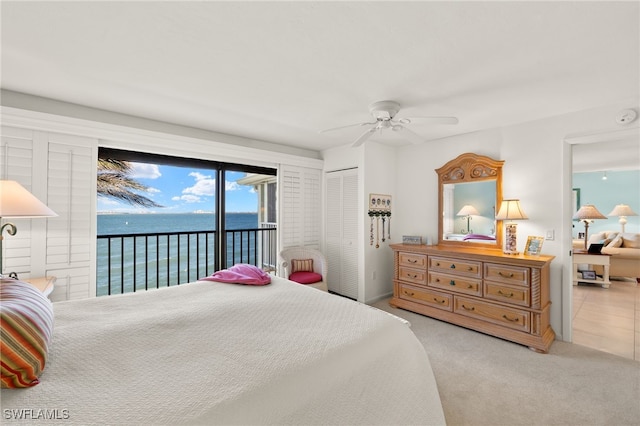 bedroom featuring a ceiling fan, carpet floors, a closet, a water view, and access to outside