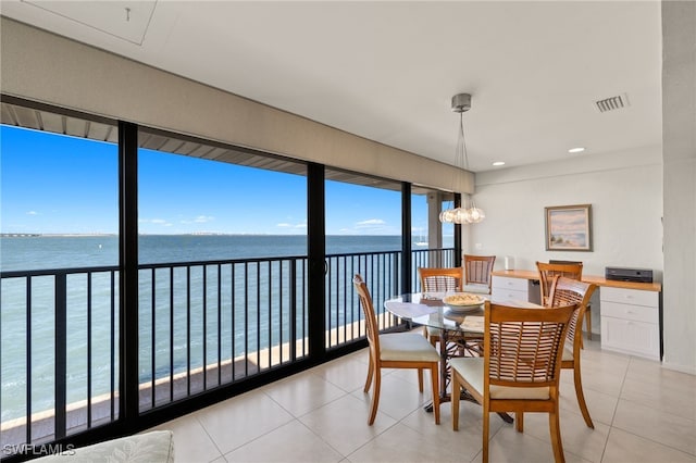 dining room featuring light tile patterned floors, visible vents, an inviting chandelier, and a water view