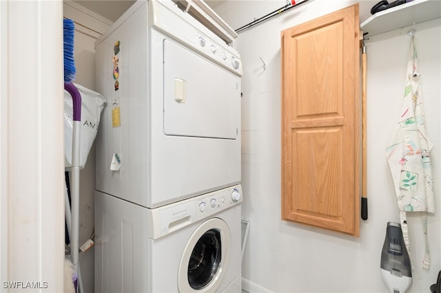 clothes washing area with stacked washer / dryer and cabinet space