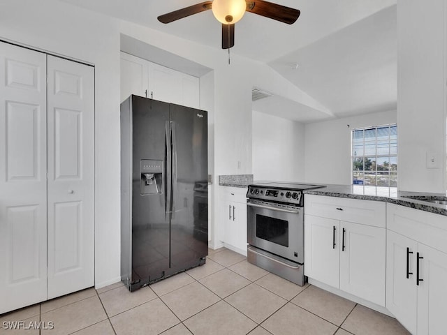 kitchen featuring dark stone countertops, light tile patterned floors, black fridge, and electric stove