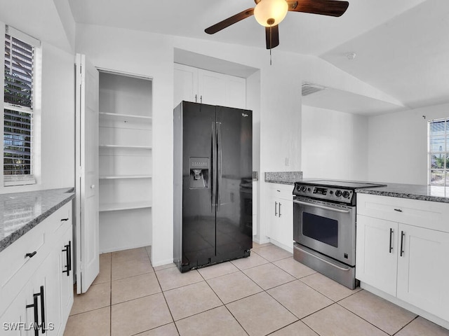 kitchen with light tile patterned flooring, stone countertops, stainless steel range with electric cooktop, white cabinetry, and black fridge