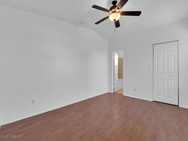 unfurnished bedroom with a ceiling fan, wood finished floors, baseboards, lofted ceiling, and connected bathroom