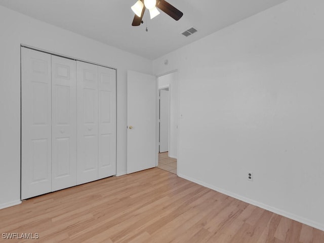 unfurnished bedroom featuring wood finished floors, visible vents, a closet, and baseboards