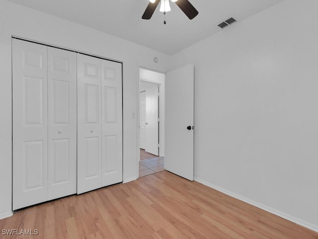 unfurnished bedroom featuring visible vents, ceiling fan, baseboards, light wood-type flooring, and a closet