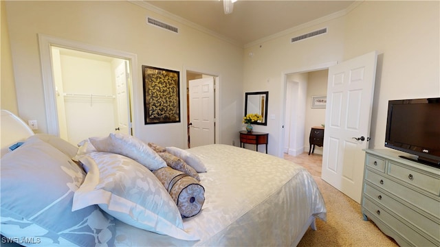 bedroom featuring light carpet, ornamental molding, a walk in closet, and visible vents