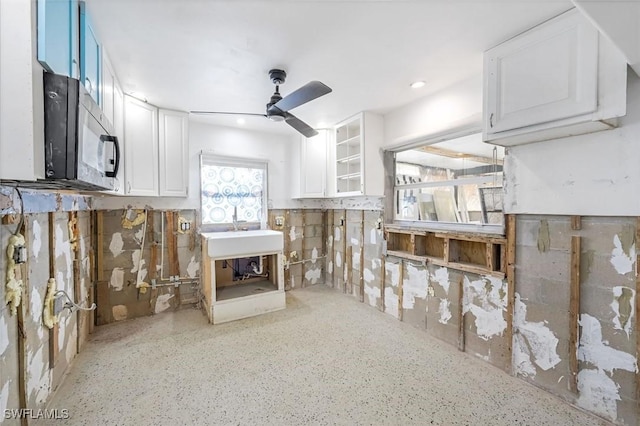 kitchen with a ceiling fan, black microwave, white cabinets, and glass insert cabinets