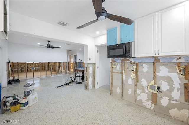 interior space featuring black microwave, visible vents, ceiling fan, and white cabinetry