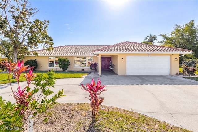 single story home with a garage, concrete driveway, a tile roof, and stucco siding